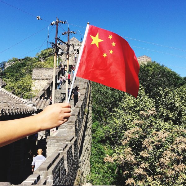 Hand holding flag of China in the Great Wall of China