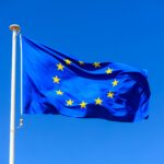 EU flag. European Union flag on a pole waving on blue sky background